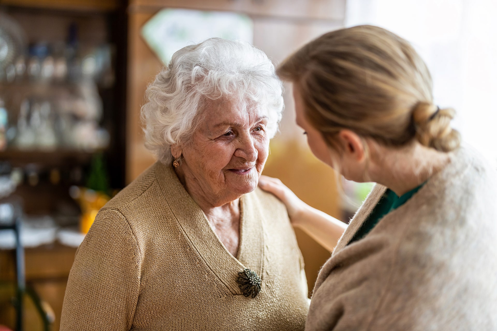 Caregiver comforting an older woman with dementia in a memory care community