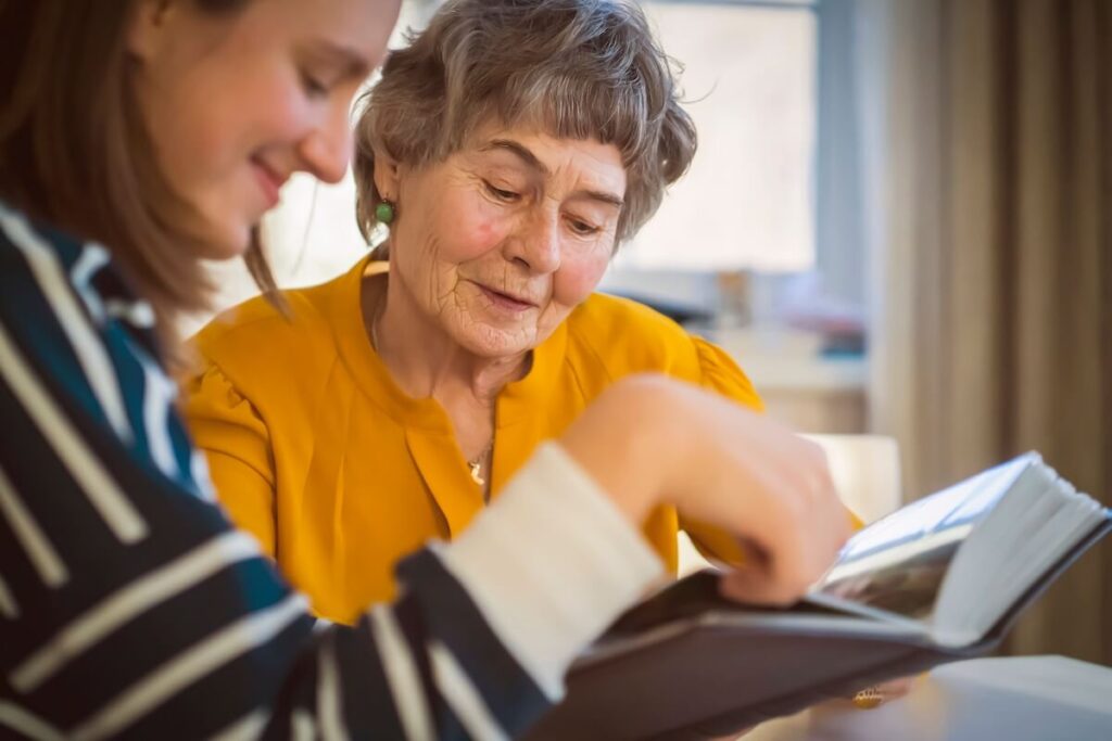 Adult daughter and her mom going through a photo album