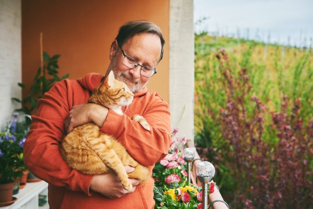 Older man holding a kitten in his arms