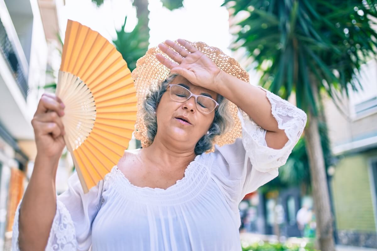 Older woman using a hand fan to avoid overheating